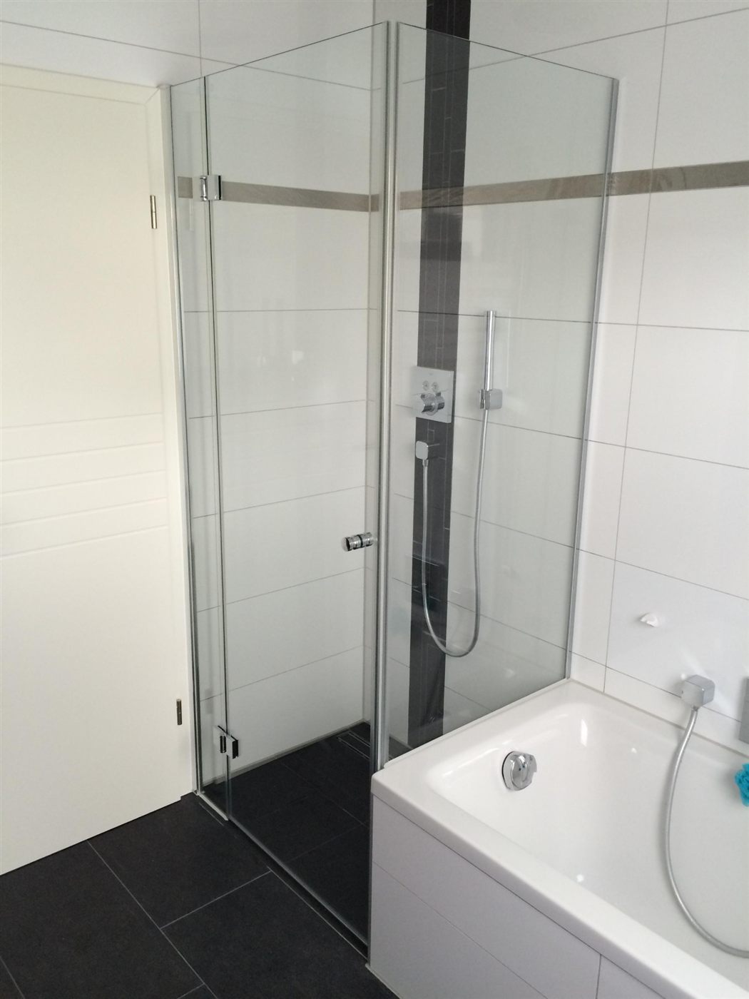 Glas-Duschabtrennung mit Tür neben einer Badewanne