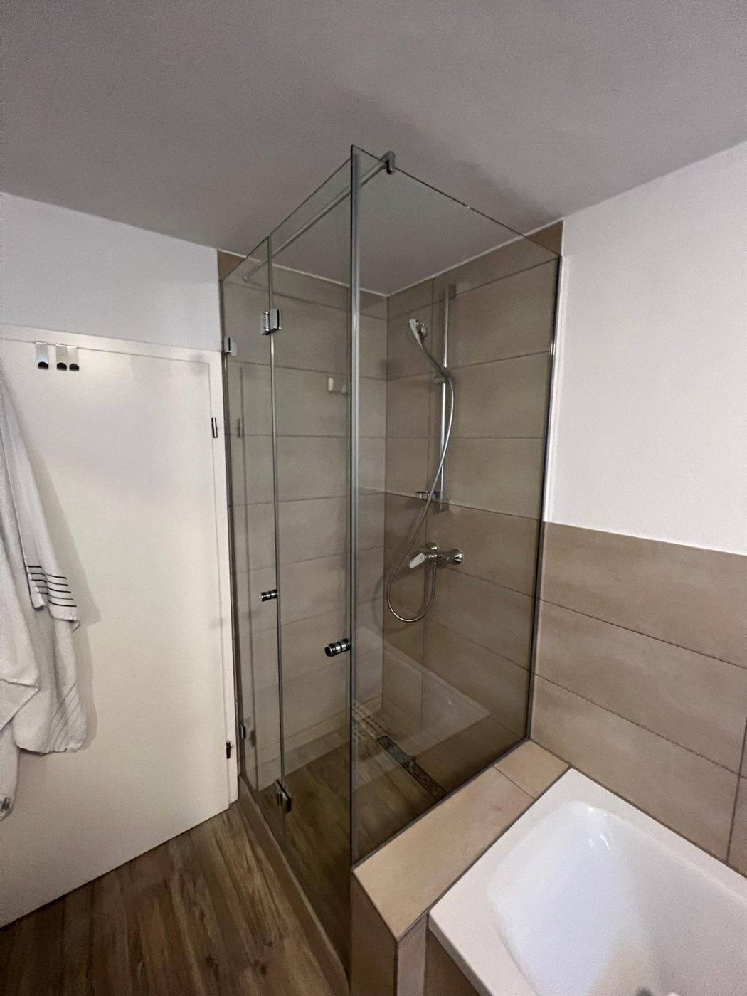 Montierte Glas-Duschkabine mit Falttür neben einer Badewanne