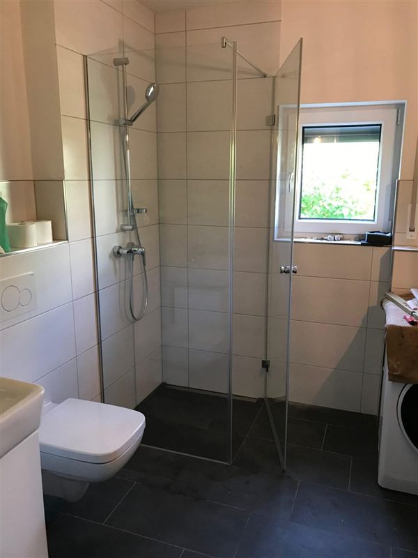 Bodengleiche Dusche mit Glaswand auf dunklen Bodenfliesen