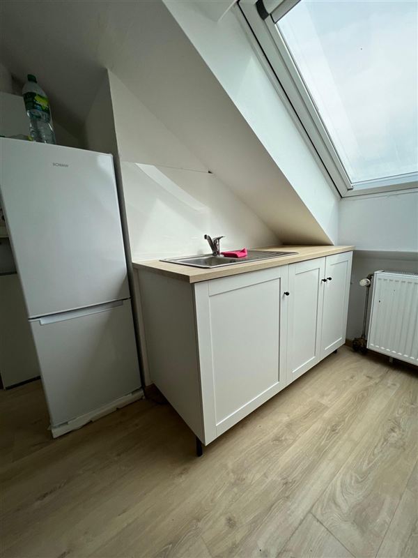 Heller Holzoptik-Bodenbelag in einer Dachgeschosswohnung mit Küchenzeile