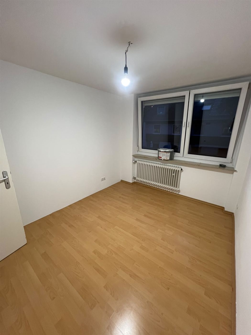 Zimmer mit hellem Laminatboden und Doppelfenster nach der Verlegung